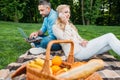 smiling young couple using smartphone and laptop at picnic Royalty Free Stock Photo