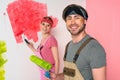 smiling young couple in working overalls with painted faces holding paint Royalty Free Stock Photo