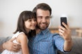 Smiling young dad and little daughter making selfie on smartphone Royalty Free Stock Photo