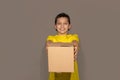 Smiling young delivery teen boy man holding and carrying a cardboard box package on gray background in studio Royalty Free Stock Photo