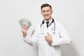 Smiling young doctor man isolated on white background. Male doctor in medical uniform showing thumbs up, holding bundle Royalty Free Stock Photo