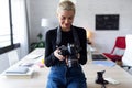 Smiling young entrepreneur woman reviewing her last photographs in the camera while sitting in the office Royalty Free Stock Photo