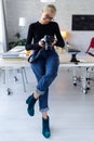 Smiling young entrepreneur woman reviewing her last photographs in the camera while sitting in the office Royalty Free Stock Photo