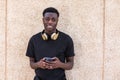 Smiling young ethnic man with headphones on neck using smartphone Royalty Free Stock Photo