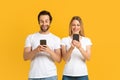 Smiling young european family in white t-shirts typing on phones, chatting in social networks Royalty Free Stock Photo