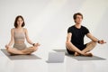 Smiling young european guy and lady in sportswear meditating, practice yoga on mat with laptop Royalty Free Stock Photo