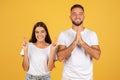 Smiling young european man and woman in white t-shirts with crossed fingers hoping or wishing Royalty Free Stock Photo