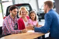 Smiling young family with car dealer Royalty Free Stock Photo