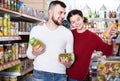 smiling young family choosing purchasing canned food for week at supermarket Royalty Free Stock Photo