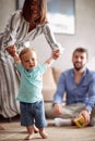 Smiling young family playing and baby learning to walk at home Royalty Free Stock Photo