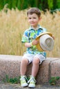 Smiling young fashion boy holding his hat while Royalty Free Stock Photo