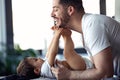 Smiling young father has fun with little baby while changing his nappy at home