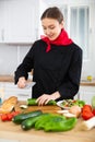 Smiling female chef in black uniform preparing vegetable salad in private kitchen Royalty Free Stock Photo