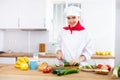Smiling female chef in white uniform preparing vegetable salad in private kitchen Royalty Free Stock Photo