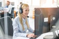 Smiling young female customer service representative with headset in call center office. Royalty Free Stock Photo