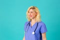 Smiling young female doctor or nurse wearing blue scrubs and stethoscope looking to side Royalty Free Stock Photo