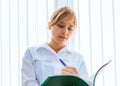 Smiling young female doctor writing medical reports Royalty Free Stock Photo