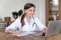 Female doctor with stethoscope working on laptop, writing report or email. Royalty Free Stock Photo