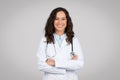 Smiling young female doctor wearing white uniform and stethoscope standing with folded arms and smiling Royalty Free Stock Photo