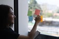 Young female employee writing on sticky notes for creation strategy of working project on glass wall. Royalty Free Stock Photo