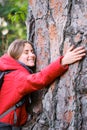 Smiling environmentalist hugging a tree in the forest.