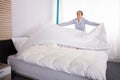 Housekeeper Arranging Bedsheet On Bed