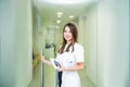 Smiling young female medical professional, doctor with stethoscope and smart phone looking at camera and opening the door to her Royalty Free Stock Photo