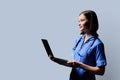 Female nurse using laptop, profile view on gray studio background Royalty Free Stock Photo