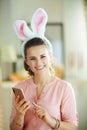 Smiling female using phone in modern house in sunny spring day Royalty Free Stock Photo