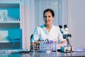 Young female scientist using microscope and looking at camera while working in the laboratory Royalty Free Stock Photo