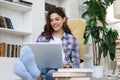 Smiling young female sitting on the floor in the living room student studying at home working with her laptop Royalty Free Stock Photo