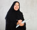 Cheerful young muslim student dressed in black hijab holding textbooks