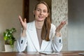 A smiling young female teacher in a white jacket conducts an online lesson while looking at the camera Royalty Free Stock Photo