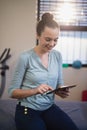 Smiling young female therapist using digital tablet while sitting on bed