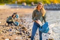 Smiling Young Female Volunteer holding bottle and garbage bag at beach