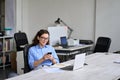 Smiling young female worker using cellphone working in office sitting at desk. Royalty Free Stock Photo