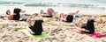 Young females training yoga positions on beach