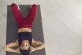 Smiling young fitness slim woman in sportswear sitting on fitmess mat and looking at camera