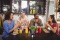 Smiling young friends eating food while sitting at coffee shop Royalty Free Stock Photo