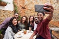 Smiling young friends taking selfies together in a cafe courtyard Royalty Free Stock Photo