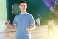 Smiling young frontenis player standing on open-air fronton court