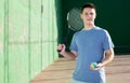 Smiling young frontenis player standing on open-air fronton court