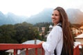 Smiling young girl with a backpack against the background of mountains.