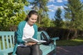 Smiling young girl with a book in the park. Photo of a college student reading a book Royalty Free Stock Photo