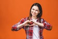 Smiling young girl in casual showing heart with two hands, love sign. Isolated over yellow background Royalty Free Stock Photo