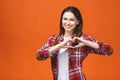 Smiling young girl in casual showing heart with two hands, love sign. Isolated over yellow background Royalty Free Stock Photo