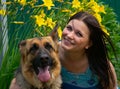 Smiling young girl with faithful friend on the background of flowers Royalty Free Stock Photo