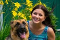 Smiling young girl with faithful friend on the background of flowers Royalty Free Stock Photo