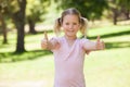 Smiling young girl gesturing thumbs up at park