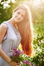 Smiling young girl holding a bunch of lupine flowers on sunny summer field